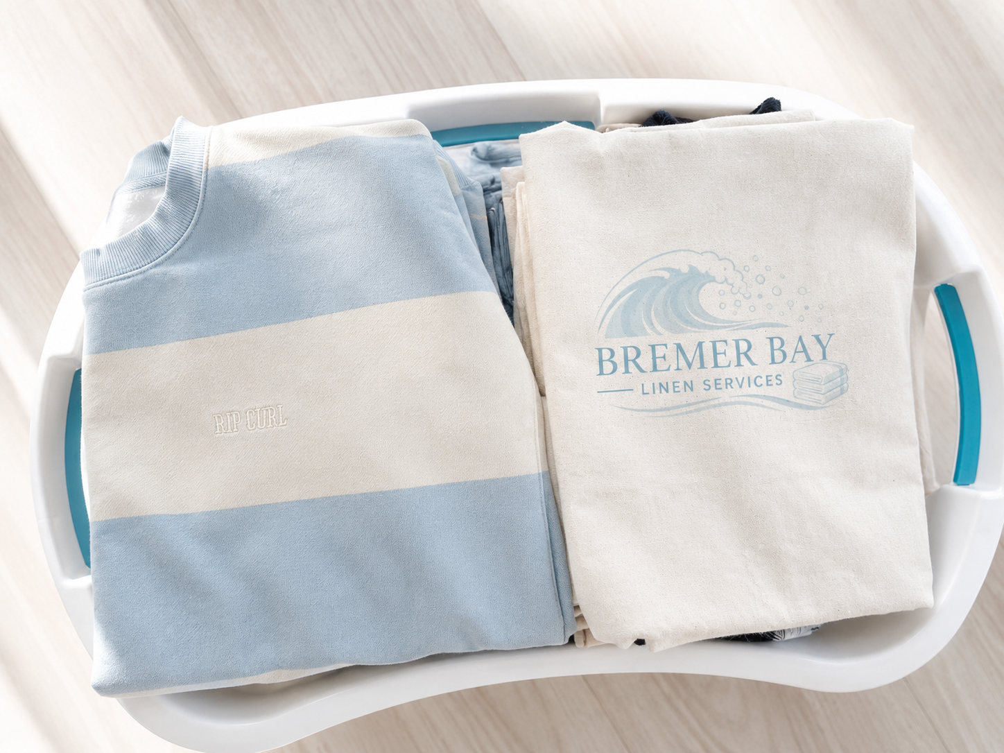 Freshly folded linen and a branded Bremer Bay Linen Services bag in a laundry basket